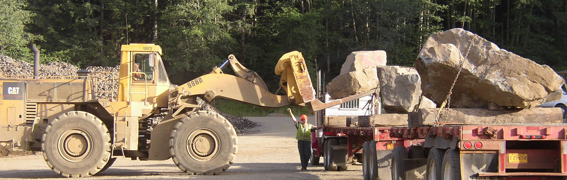 articulated loader placing large rock on truck